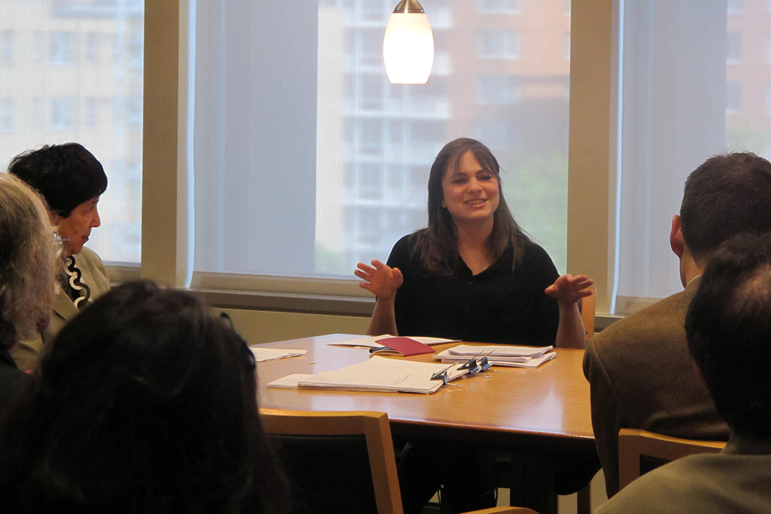 A small group of students and professors sit at a table having a discussion